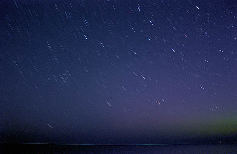 Time exposure of stars above a Lake Michigan beach.